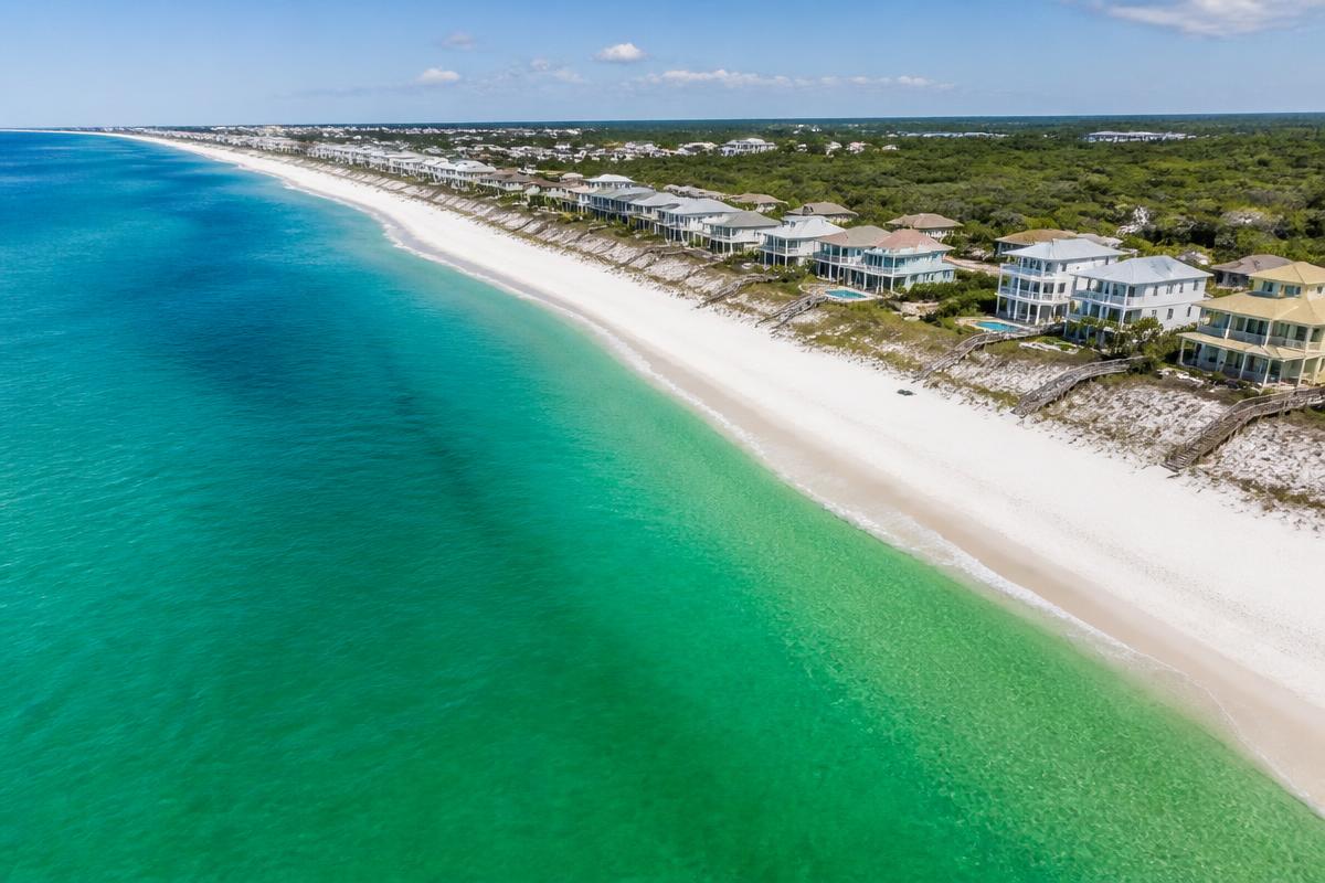 Aerial view of emerald Gulf water and white sand beach lined with coastal homes